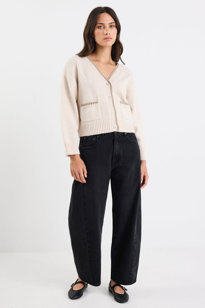Woman wearing a beige cardigan and black pants on a white background