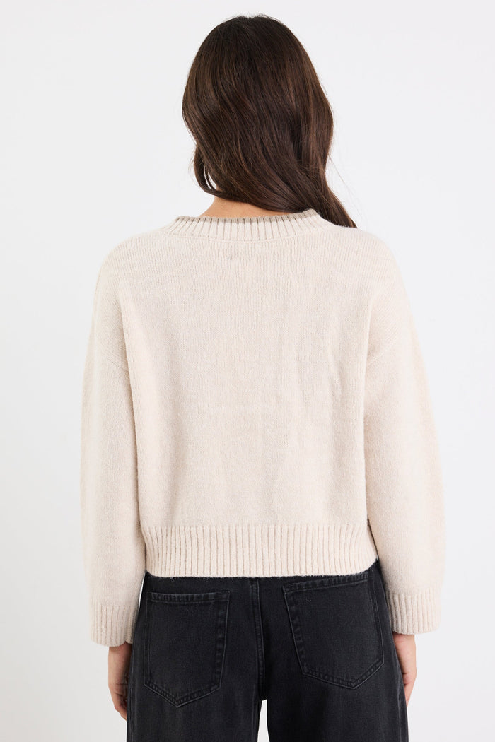 Person wearing a cream sweater and black pants on a white background
col_pattern
