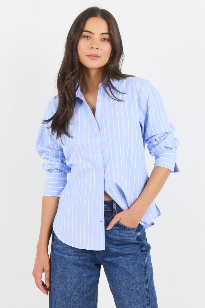Woman wearing a light blue striped shirt and jeans on a white background