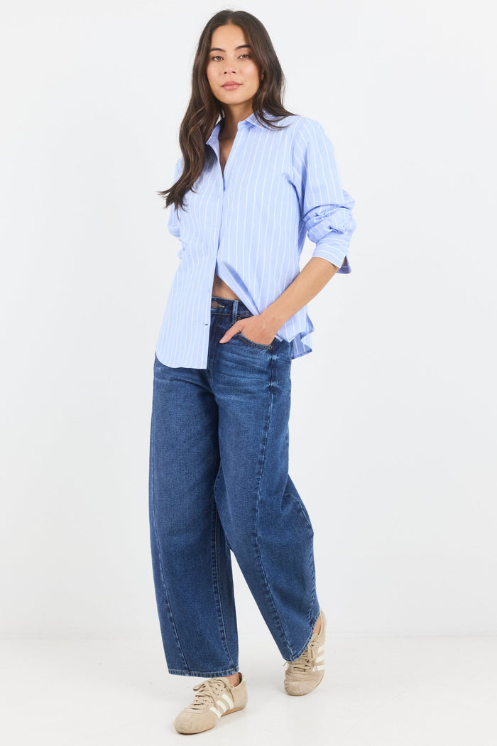 Woman wearing a light blue striped shirt and blue jeans on a white background