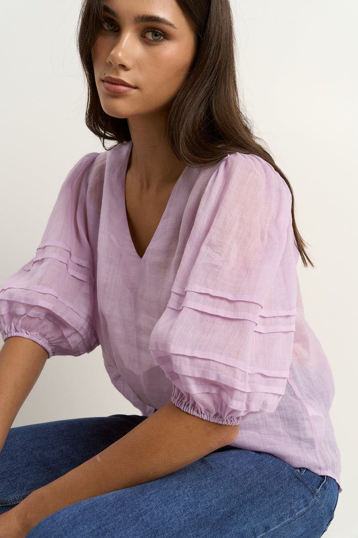 model wears a purple linen blouse with dark blue jeans