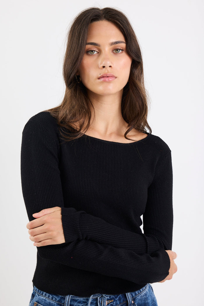 Woman wearing a black sweater and blue jeans against a white background