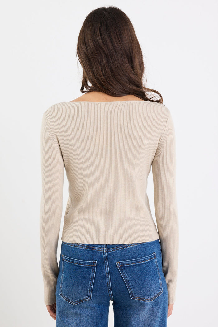 Woman wearing a beige sweater and blue jeans on a white background