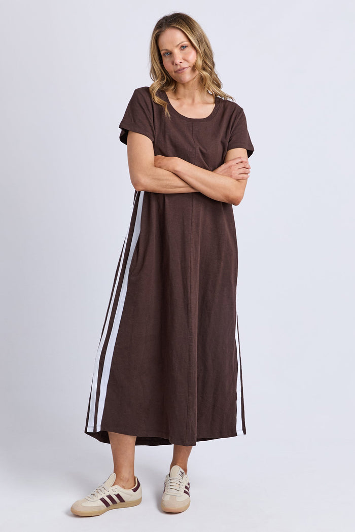 Woman wearing a brown dress with white stripes on a plain background