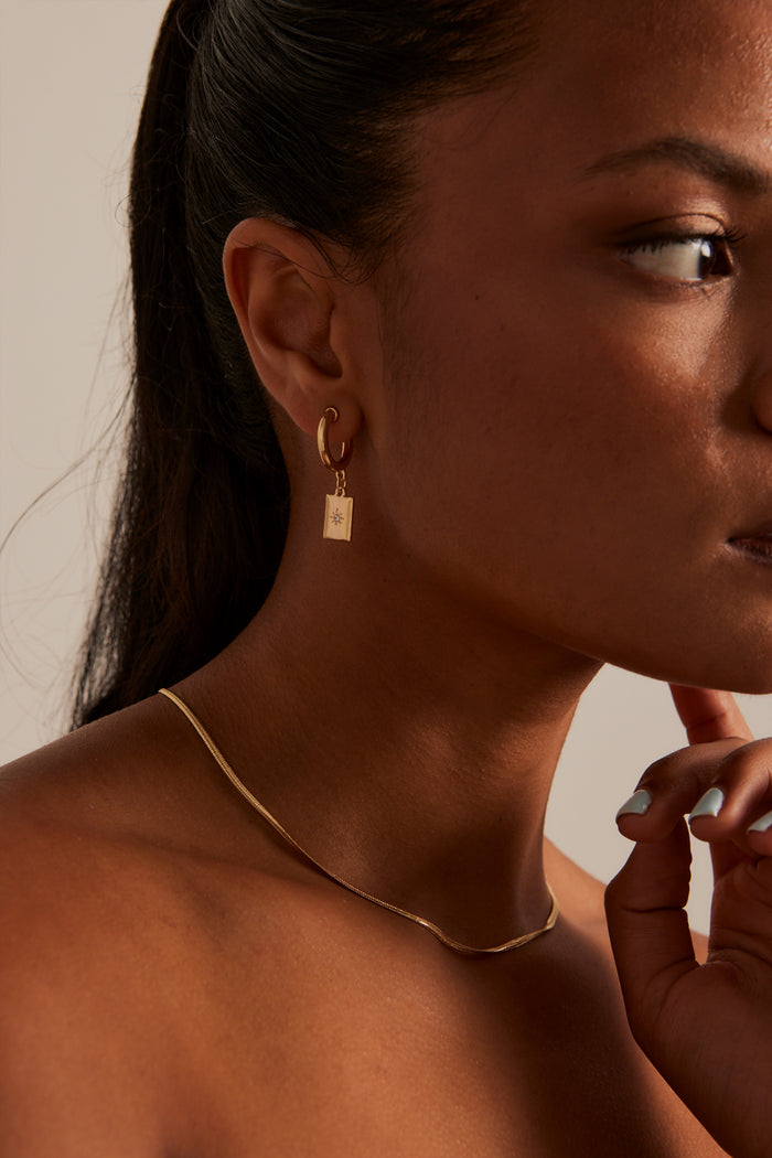 Model wears gold pendant earring