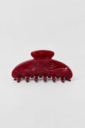 A glossy dark red hair claw clip with a marbled tortoiseshell-like finish, photographed on a clean light gray background.
