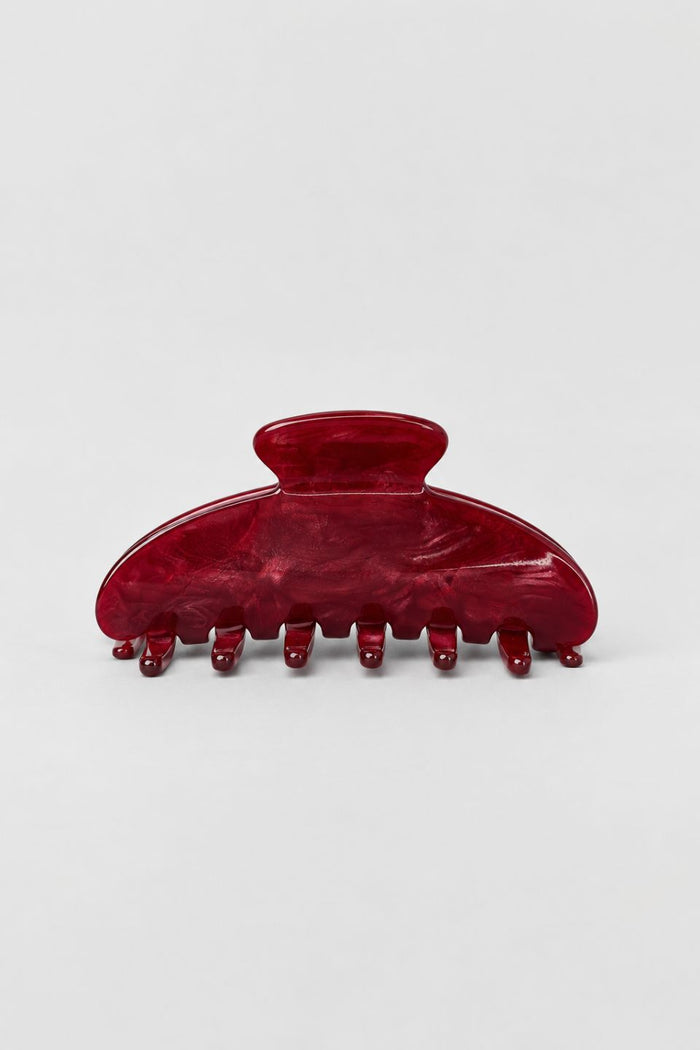 A glossy dark red hair claw clip with a marbled tortoiseshell-like finish, photographed on a clean light gray background.