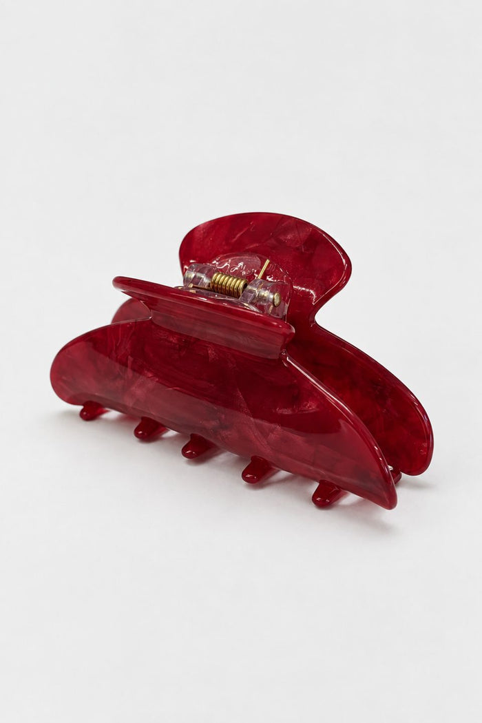A translucent red hair claw clip made of glossy marbled acrylic, shown on a clean white background.