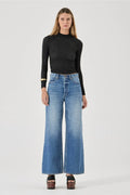 Woman wearing a black top and blue jeans on a white background