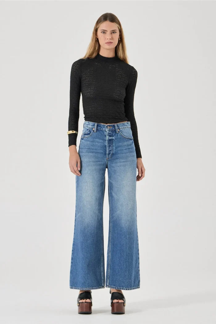 Woman wearing a black top and blue jeans on a white background