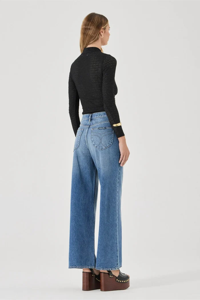 Person wearing a black top and blue jeans on a white background