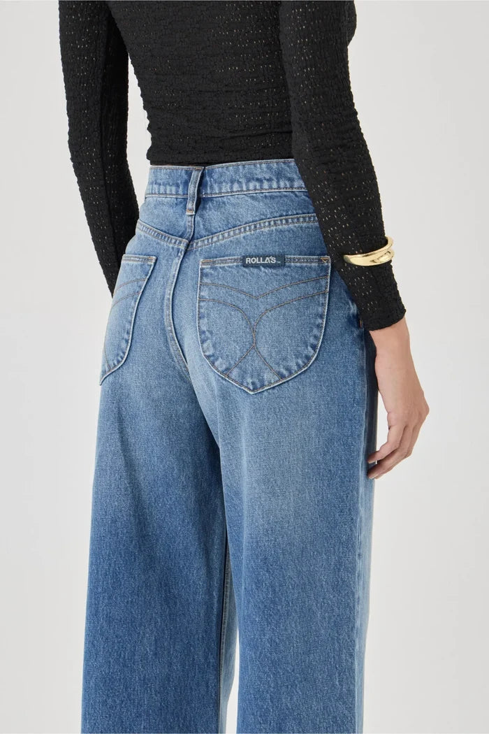 Person wearing blue jeans with a plain background