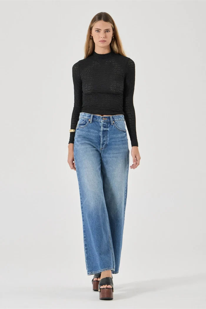 Woman wearing a black sweater and blue jeans on a white background
