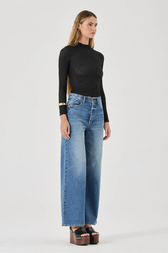 Woman wearing a black turtleneck and blue jeans on a white background