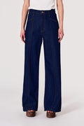 Person wearing dark blue wide-leg jeans on a white background