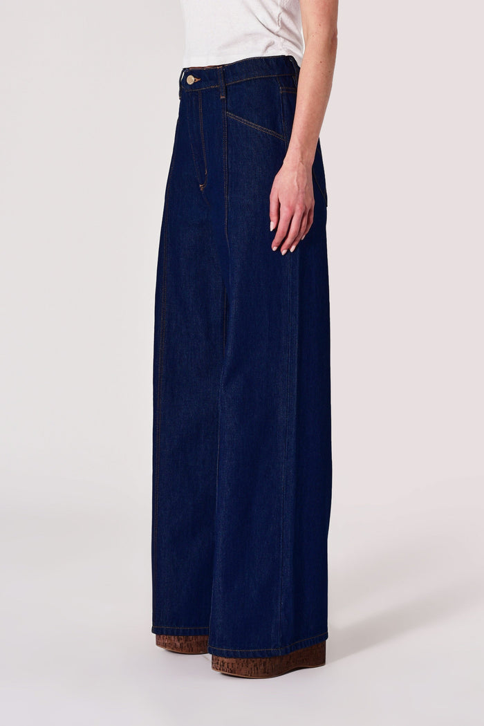 Navy blue wide-leg jeans worn by a person on a white background