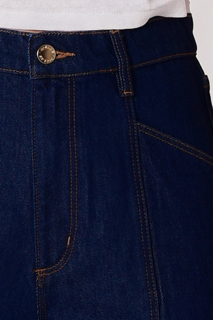 Close-up of dark blue denim pants with a gold button on a white background
col_pattern