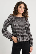 Woman wearing a black and white checkered blouse with a plain background