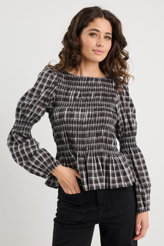 Woman wearing a black and white checkered blouse with a plain background