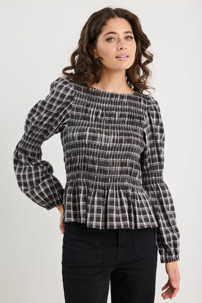 Woman wearing a black and white checkered blouse with puffed sleeves on a white background