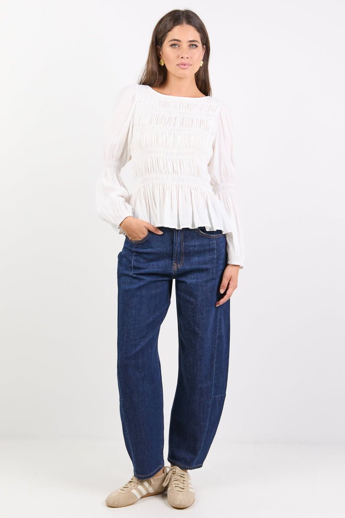 Woman wearing a white top and blue jeans on a white background