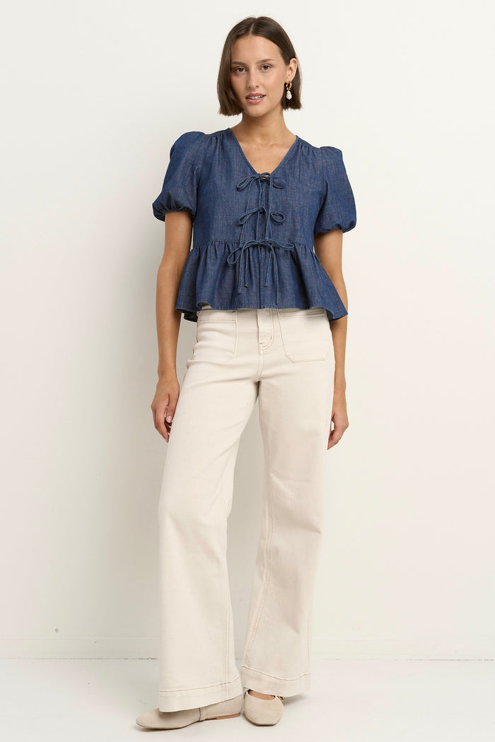model wears a blue short sleeve blouse with ecru jeans