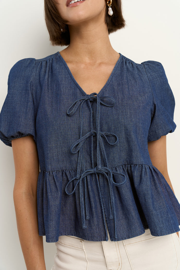 model wears a blue short sleeve blouse with ecru jeans