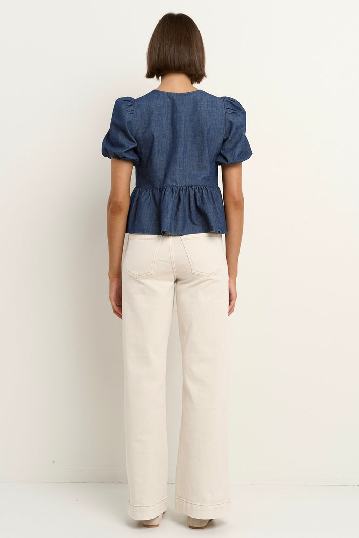 model wears a blue short sleeve blouse with ecru jeans