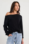 Woman wearing a black off-shoulder top and light blue jeans on a white background