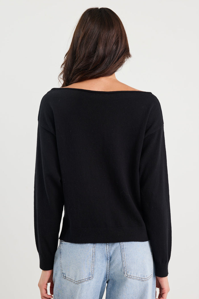 Person wearing a black long-sleeve top and light blue jeans on a white background