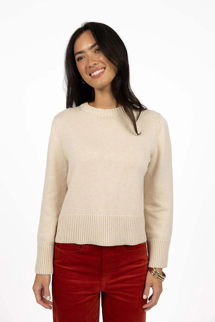 Woman wearing a beige sweater and red pants on a white background
col_pattern
