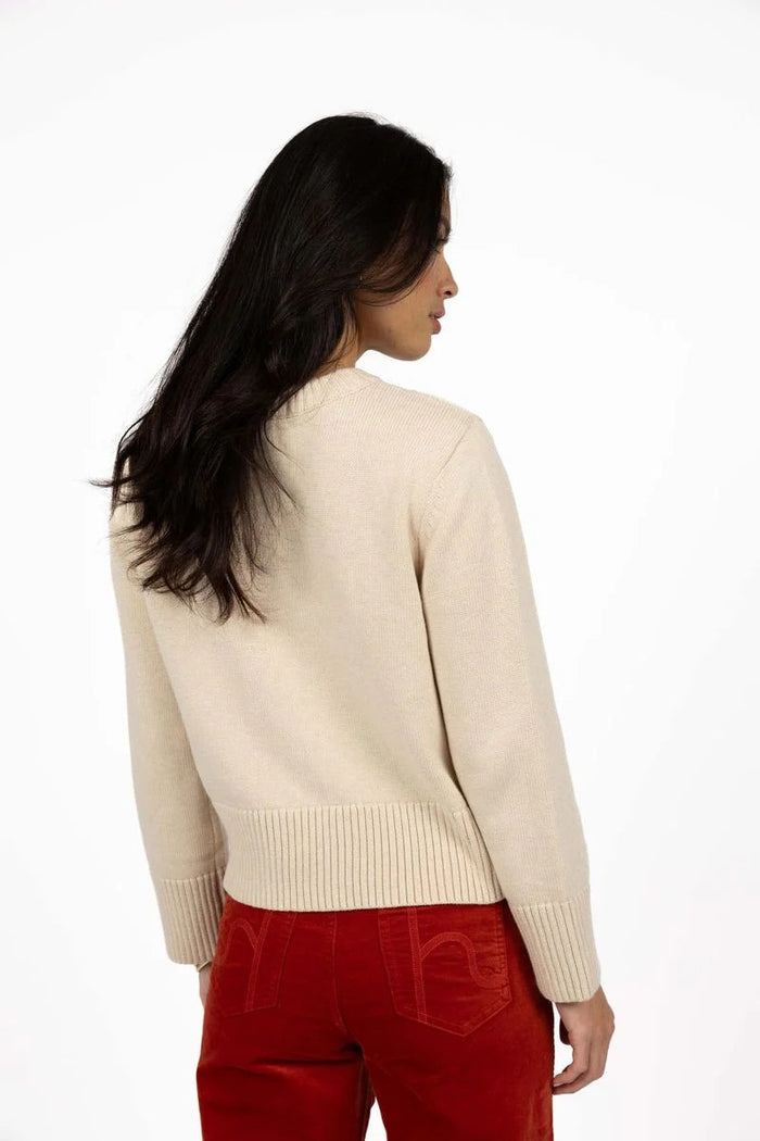 Woman wearing a beige sweater and red pants on a white background