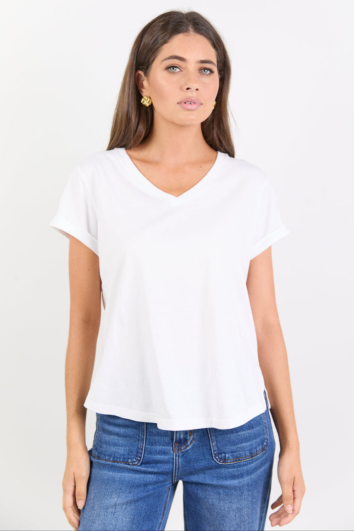 Woman wearing a white t-shirt and blue jeans on a plain background