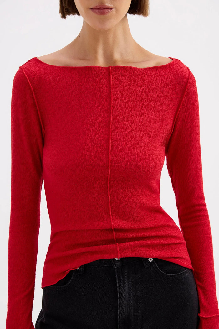 Red long-sleeve top worn by a person on a white background