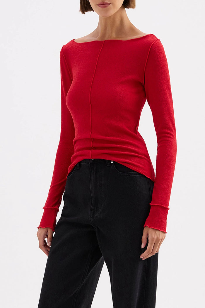 Person wearing a red long-sleeve top and black pants on a white background