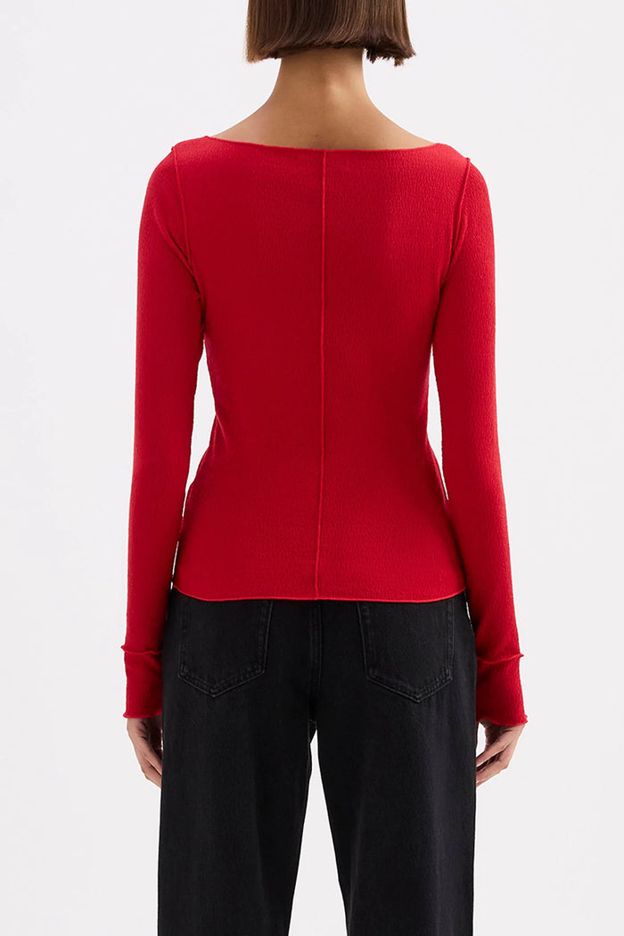 Red long-sleeve top worn by a person on a white background