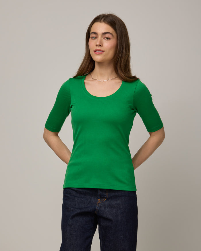 Model wearing Celine Ribbed Elbow Sleeve Tee in Verde, a bright Kelly green color. Celine Ribbed Elbow Sleeve Tee is a merino wool short sleeve, scoop neck tee available in sizes XS-3X.