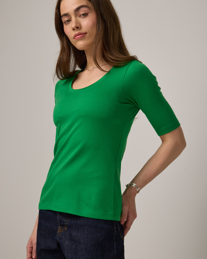 Model wearing Celine Ribbed Elbow Sleeve Tee in Verde, a bright Kelly green color. Celine Ribbed Elbow Sleeve Tee is a merino wool short sleeve, scoop neck tee available in sizes XS-3X.