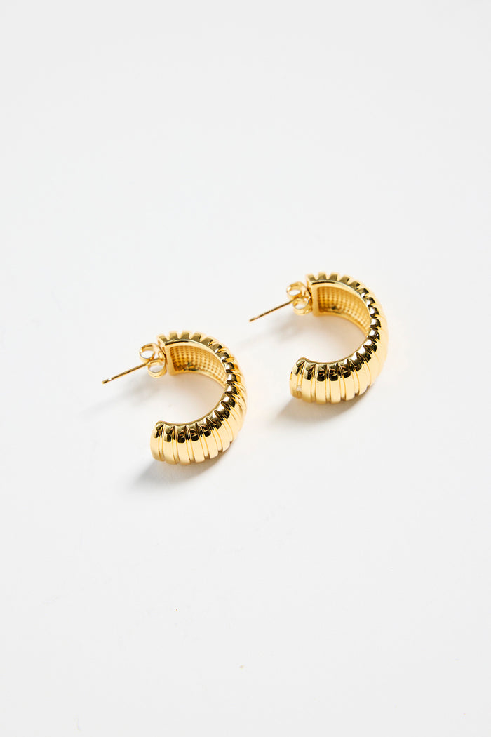 gold-plated brass huggie earrings with a ridged design, photographed flat on a white background.