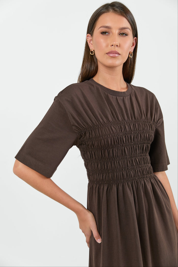 Woman wearing a brown dress against a white background
