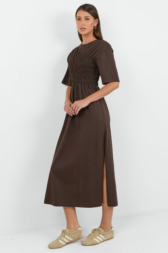 Woman wearing a brown dress with a plain white background