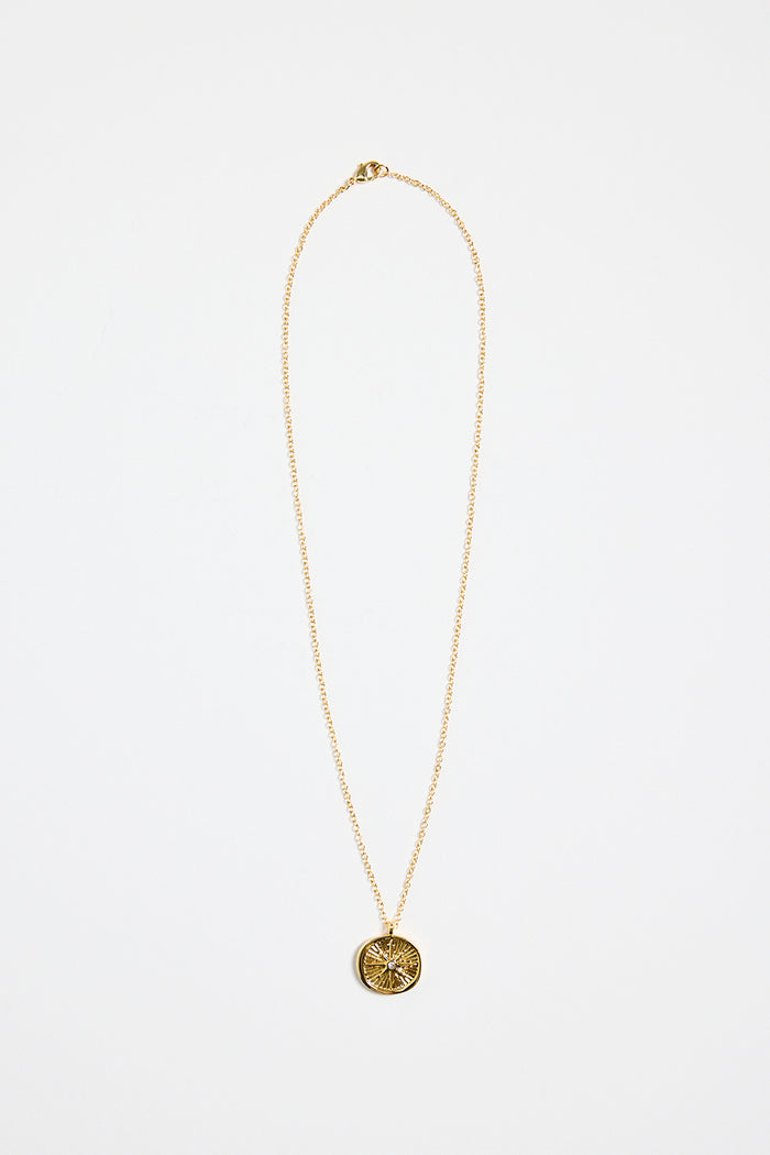gold-plated necklace with fine chain and a round sunburst pendant featuring a central gem detail,