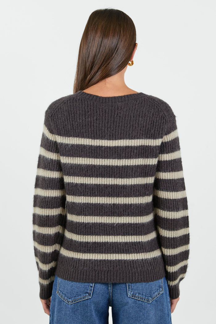 Person wearing a striped sweater and jeans on a white background