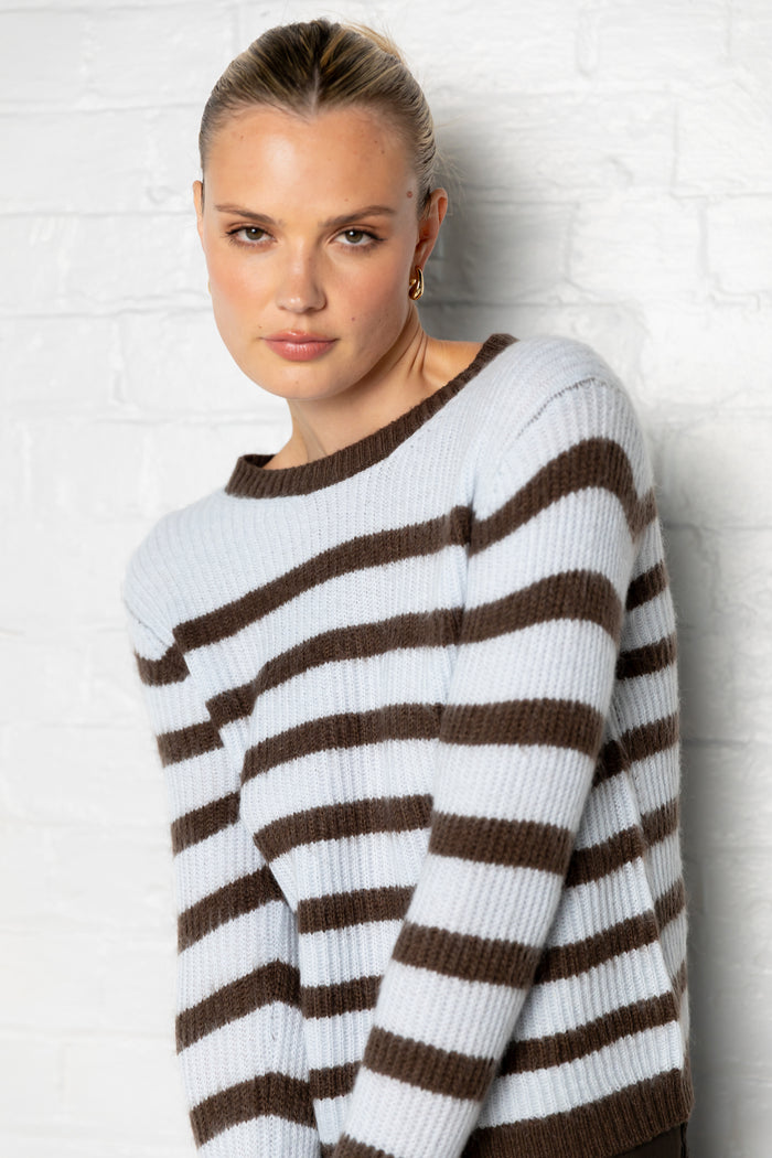 Woman wearing a brown and white striped sweater against a light background