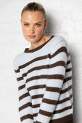 Woman wearing a brown and white striped sweater against a light background