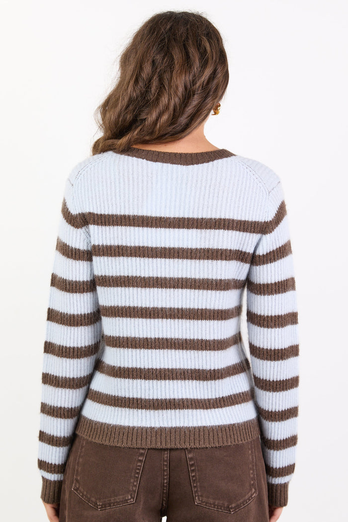 Person wearing a brown and white striped sweater with brown pants on a white background