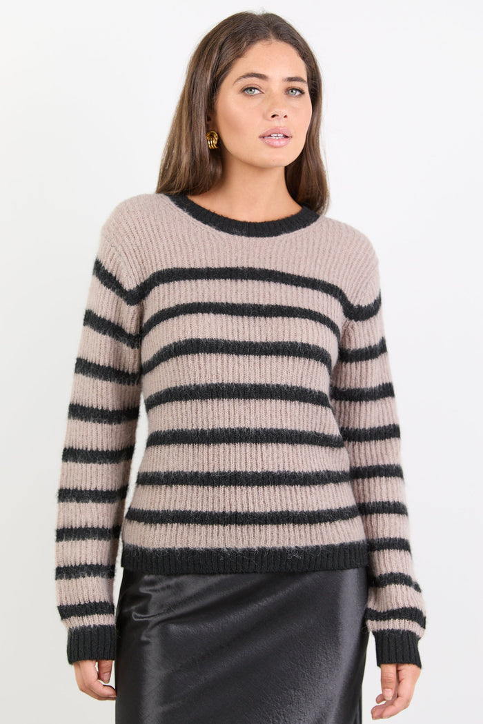 Woman wearing a beige and black striped sweater on a white background