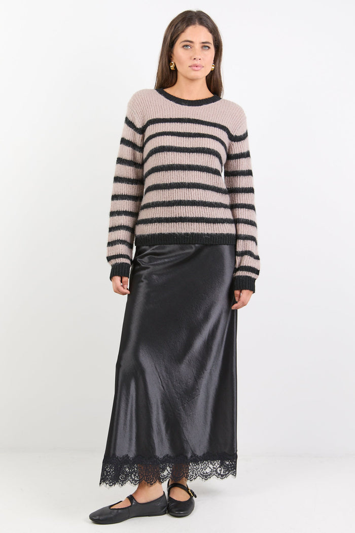 Woman wearing a striped sweater and black satin skirt on a white background