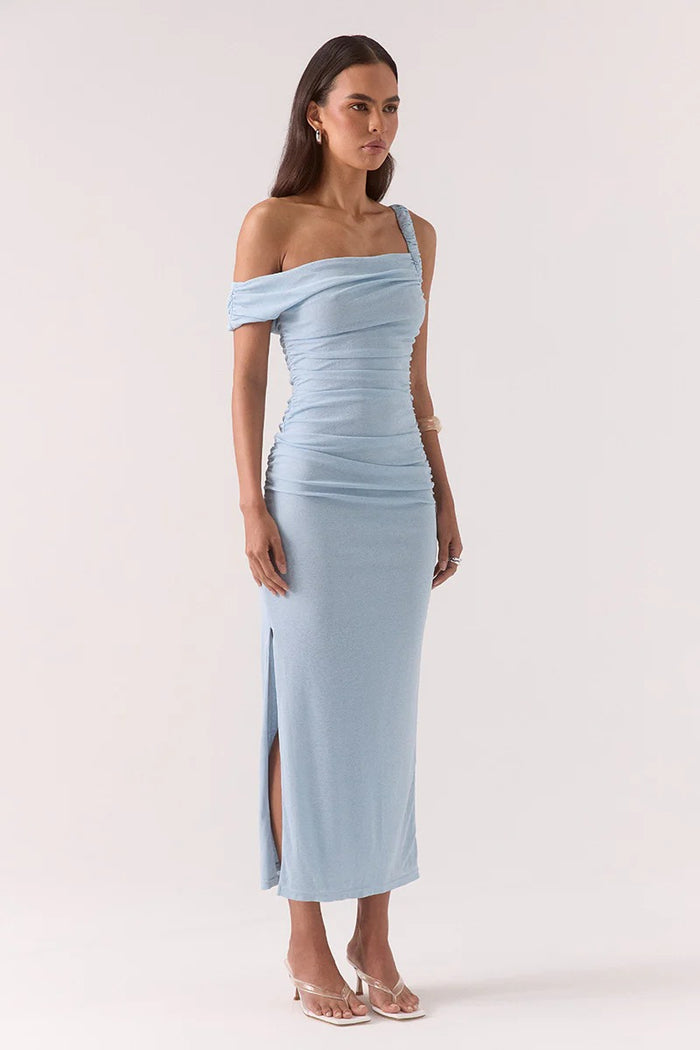 Woman wearing a light blue off-shoulder dress with a slit on a white background