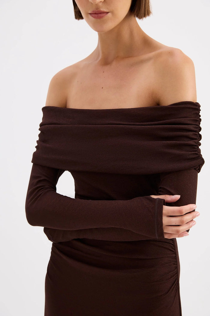 Woman wearing a brown off-shoulder dress against a white background